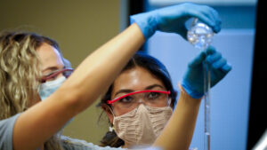 Two female students wearing masks and gogglesworking in the lab