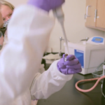 One of the Baker Research Group students wearing goggles and a lab coat working in the lab