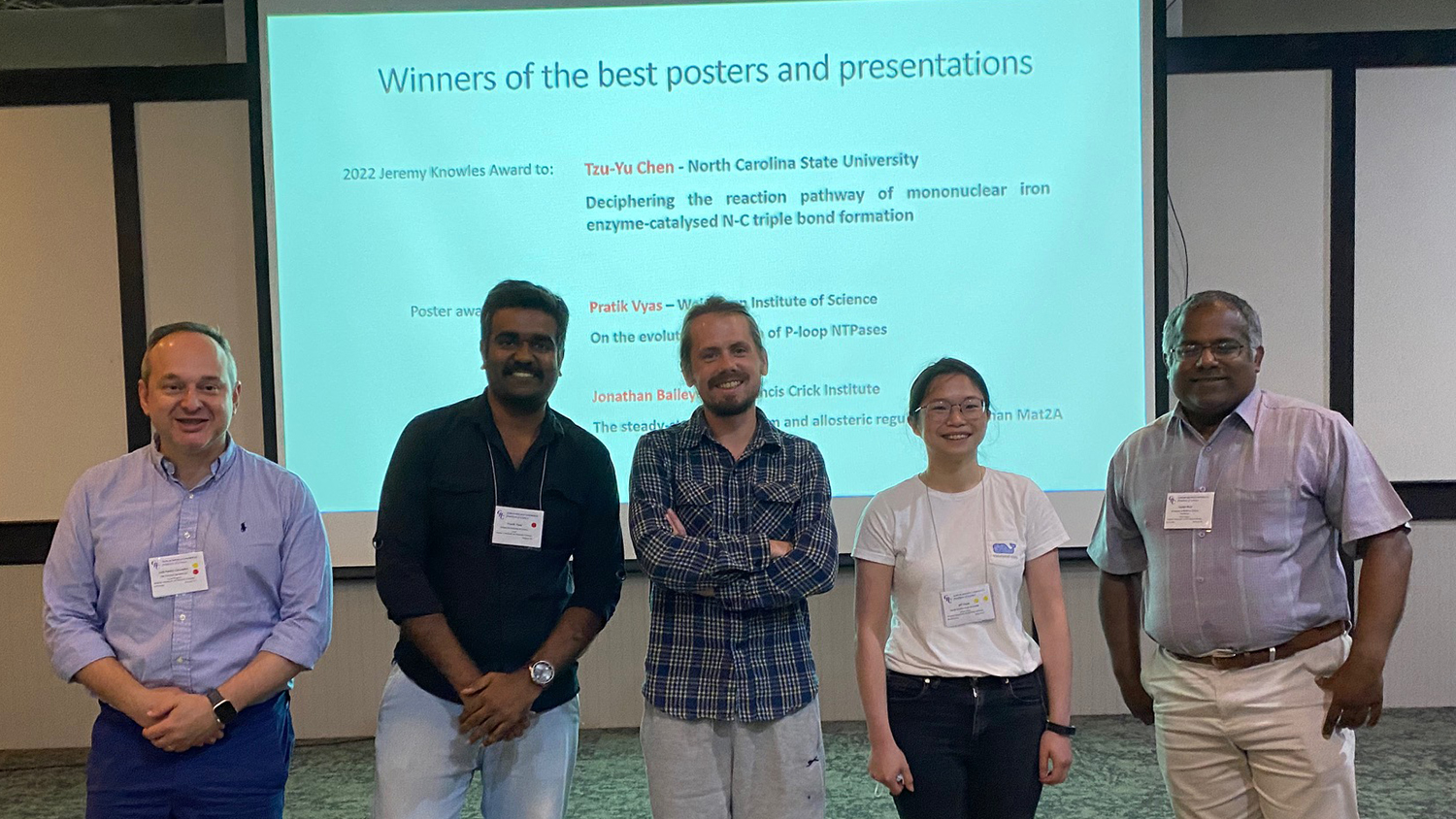 A group of the student winners of awards by the American Chemical Society. The background is a projection of a slide listing the winners' names and presentation titles.