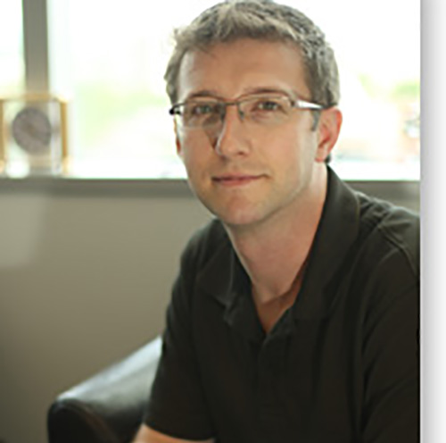 Professor Jeffrey Johnston wearing a black shirt and eyeglasses