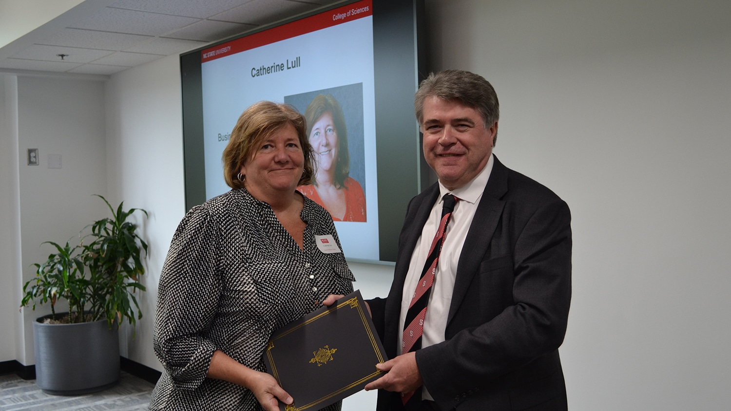 Catherine Lull receiving a recognition award from dean Lewis Owen