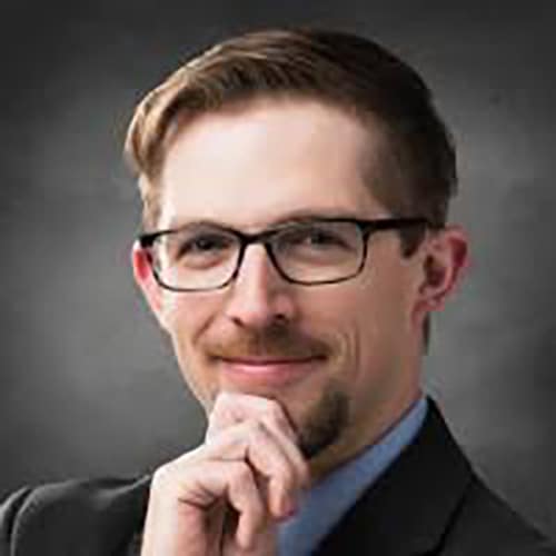 Headshot of a pensive young chemist wearing black eyeglasses