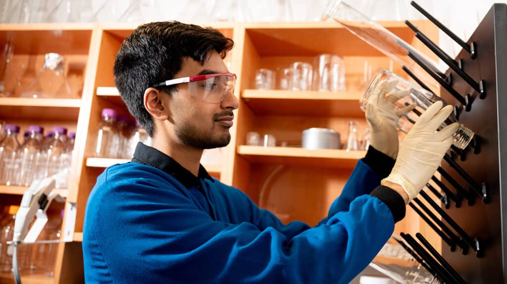 An undergraduate student in the lab organizing glassware on a hanging board