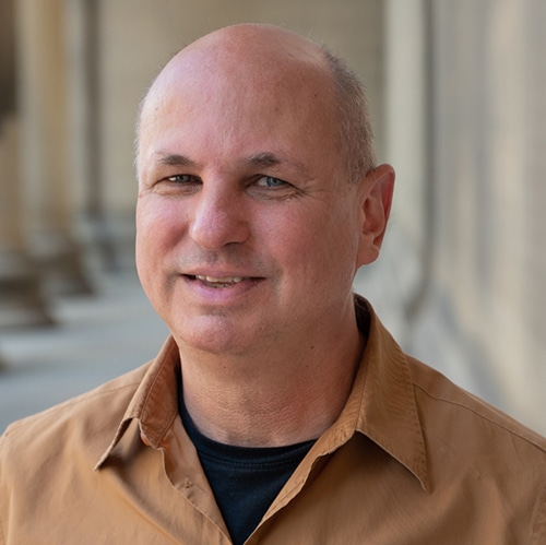 Headshot of a middle aged man wearing a light brown shirt