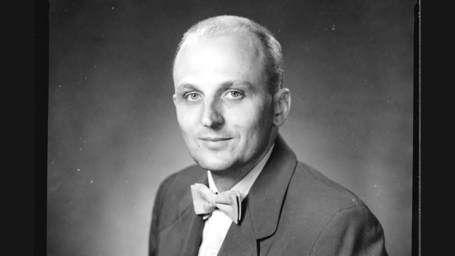 A black and white photo of an older man wearing a bow tie