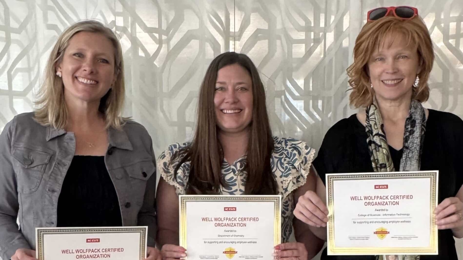 Three people holding certificates looking at the camera