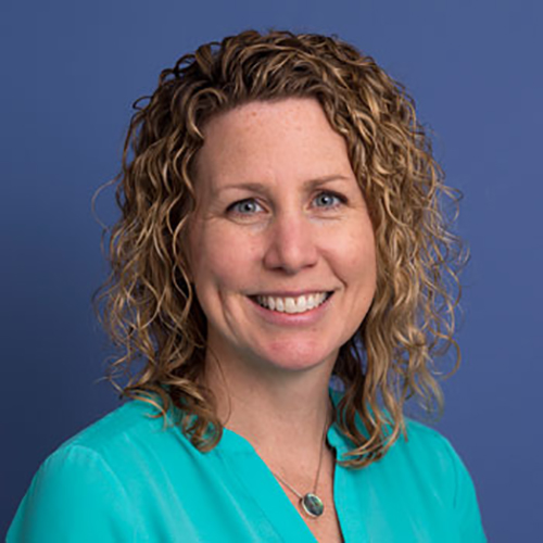 Amy Cannon, Headshot with a blue wall background