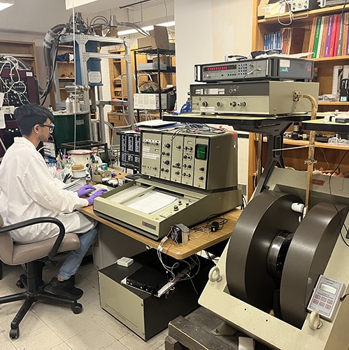 Chemistry student wearing a lab coat typing on a computer