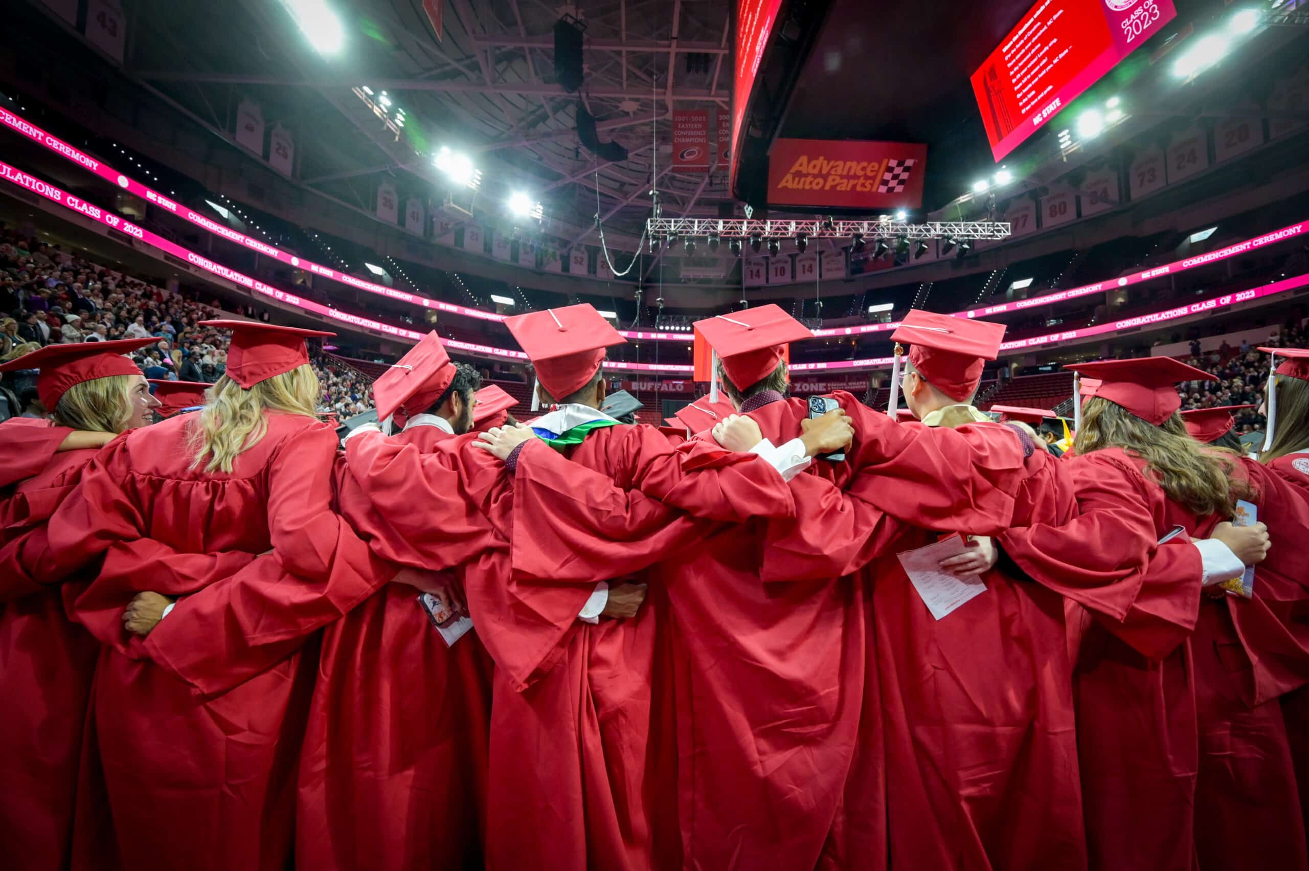NC State University students in red gowns celebrating during their graduation ceremony in the arena